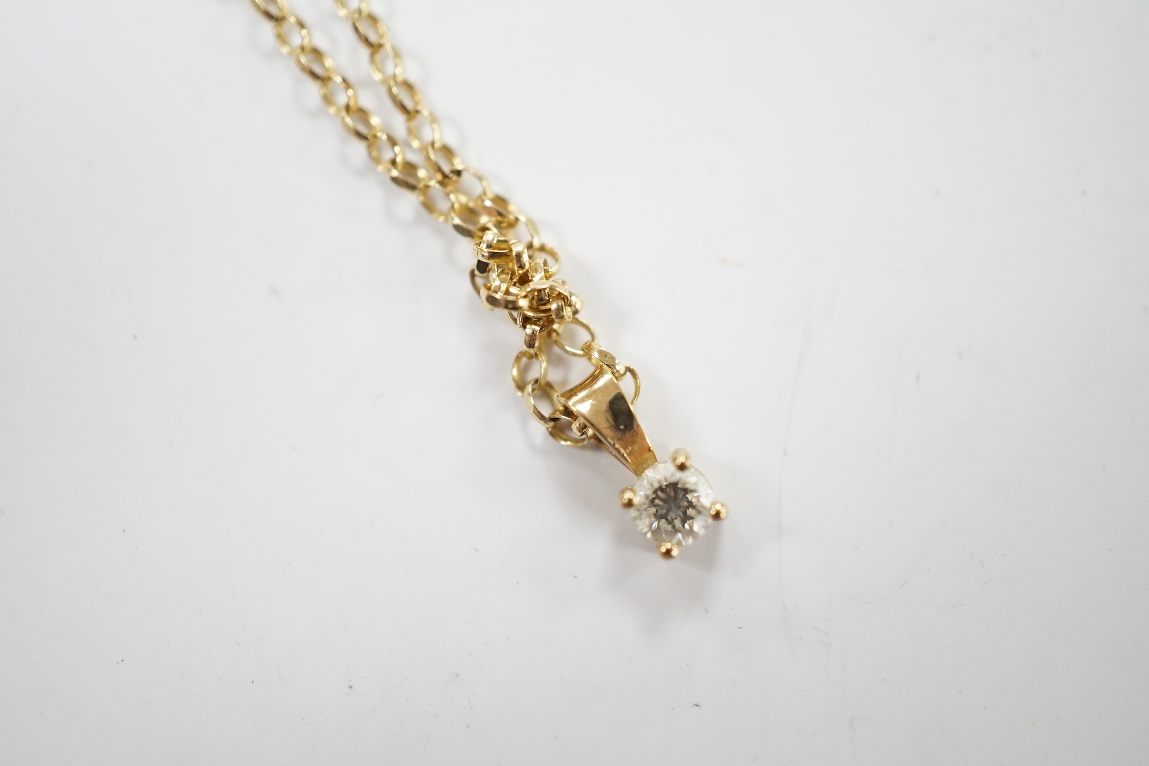 A modern 9ct gold and solitaire diamond set pendant, 9mm, on a 9ct chain, 38cm, gross weight 2.2 grams.